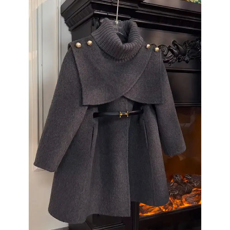 Dark gray coat with a belt hanging in front of a fireplace